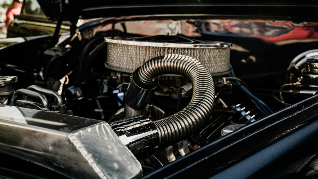 Detailed view of vintage car engine with open hood on a sunny day.