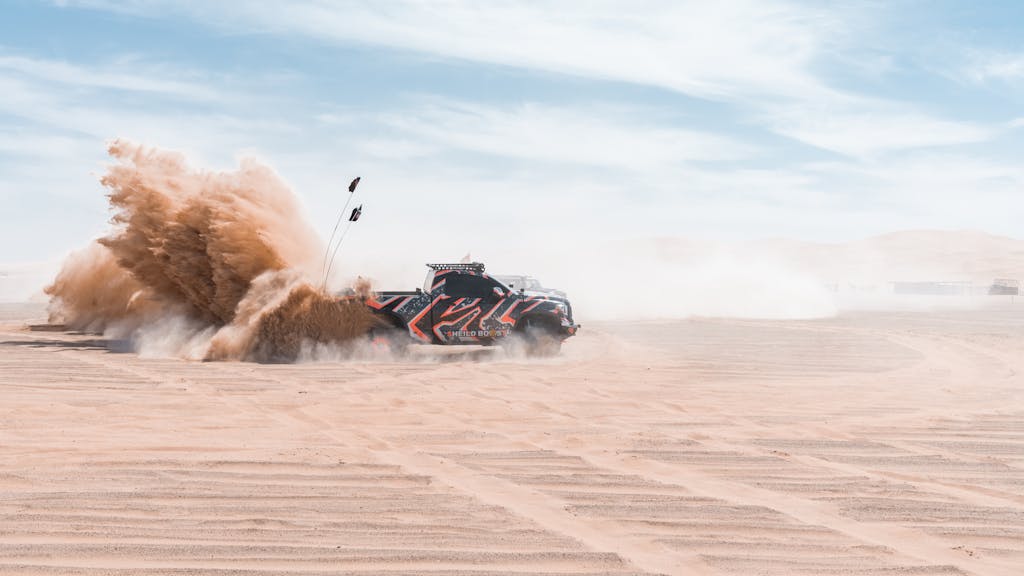 Dynamic off-road race truck kicking up sand in Abu Dhabi desert, UAE.