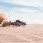 Dynamic off-road race truck kicking up sand in Abu Dhabi desert, UAE.