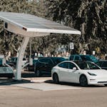 Electric car parked at a solar charging station outdoors, highlighting renewable energy and innovation.