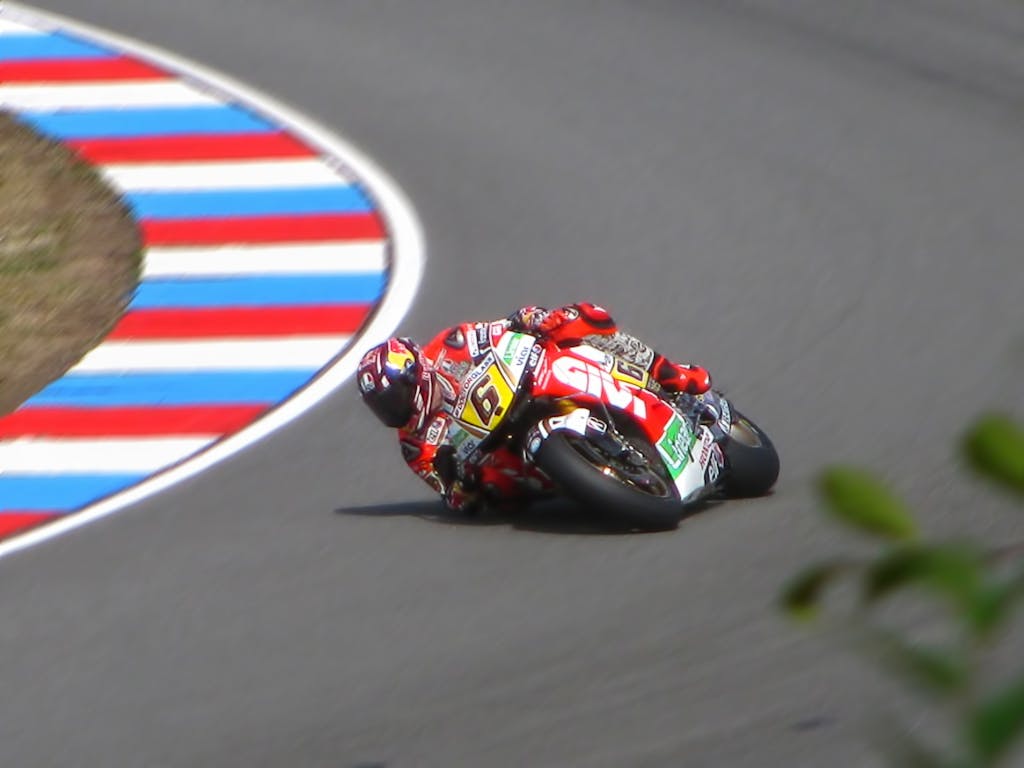 Motorcycle racer leans into a sharp curve on a high-speed track during a competition.