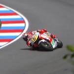 Motorcycle racer leans into a sharp curve on a high-speed track during a competition.