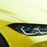 Detailed close-up of a sleek yellow car's headlight, showcasing modern design features.