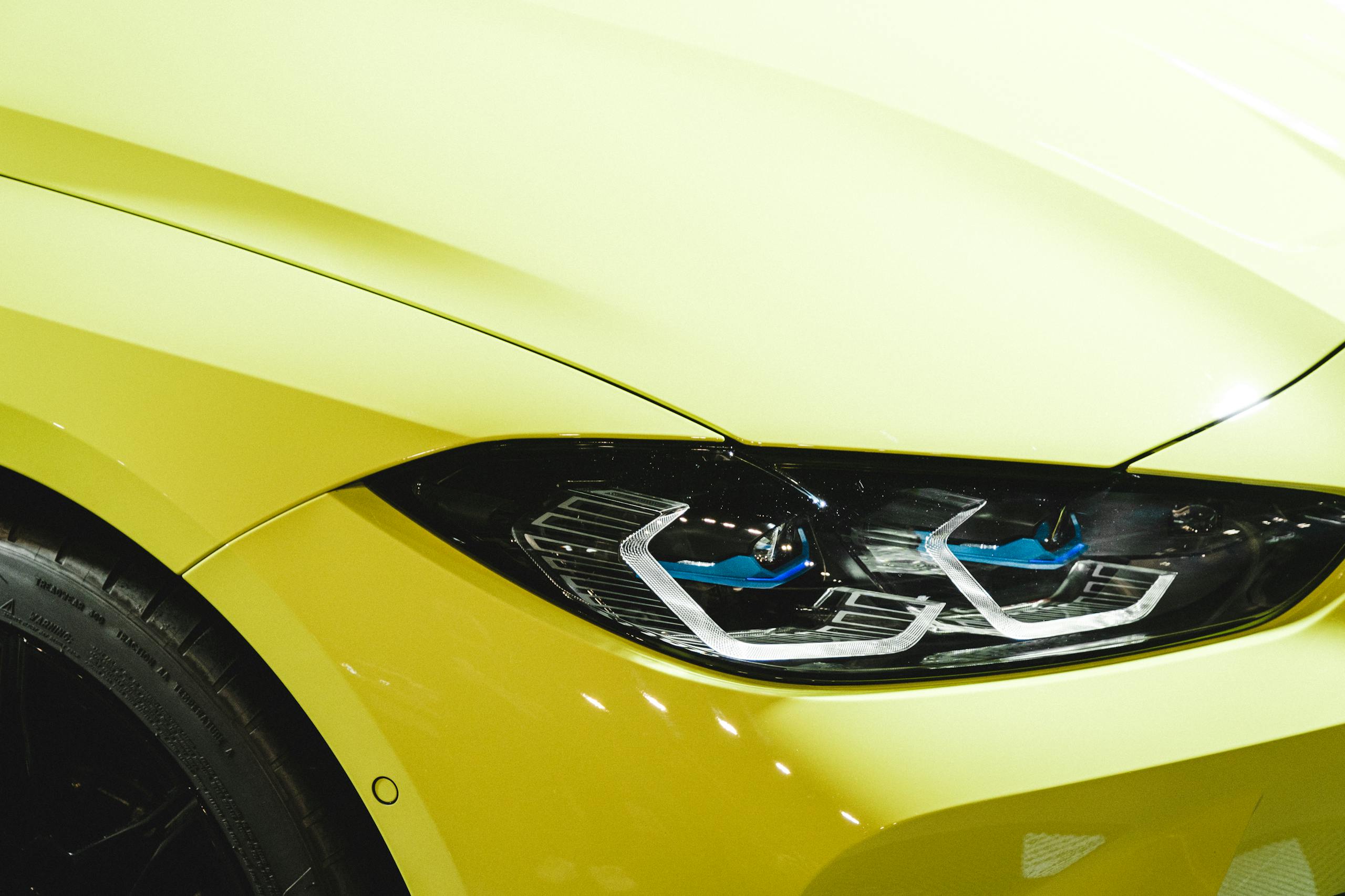 Detailed close-up of a sleek yellow car's headlight, showcasing modern design features.