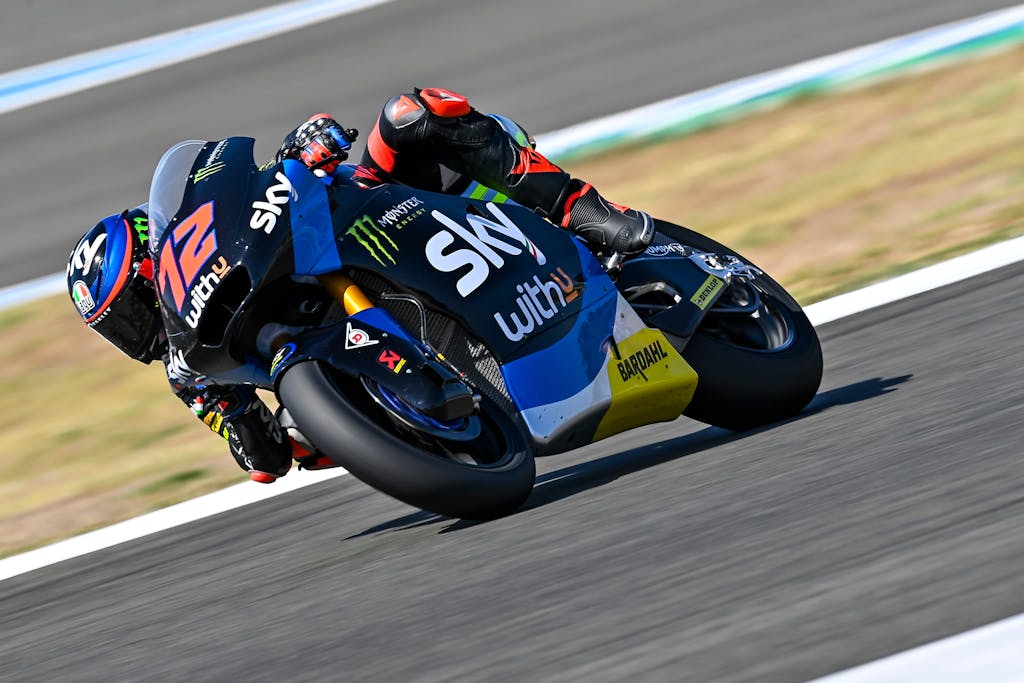 Dynamic capture of a motorcycle racing on an outdoor track with rider in sportswear.