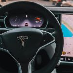 Interior view of a Tesla Model X steering through palm-lined streets of Santa Monica at twilight.